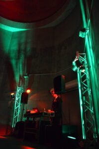 Picture of a DJ playing at Silo Park inside one of the Silos. DJ equipment, speaker system, lighting and lighting rigging / truss was hired from The Rock Factory. As it was christmas the ambient lighting was set to christmas colours - green and red.