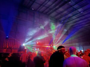 Colourful lights shining through the air above an audience - using lighting to create an epic dance party atmosphere. Sound and Lighting Hire Package.