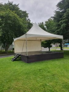An example of Marquee Hire Auckland. This picture shows a 6 by 6 springtop marquee setup on a stage outside in a park somewhere in Tamaki-Makaurau.