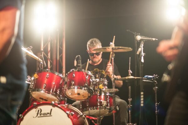 This picture shows a drummer playing our Pearl Reference Drum kit hire option.